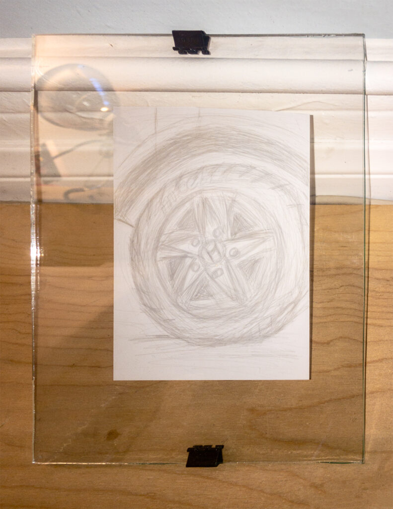 A drawing of a car tire is sandwiched between two sheets of glass.
