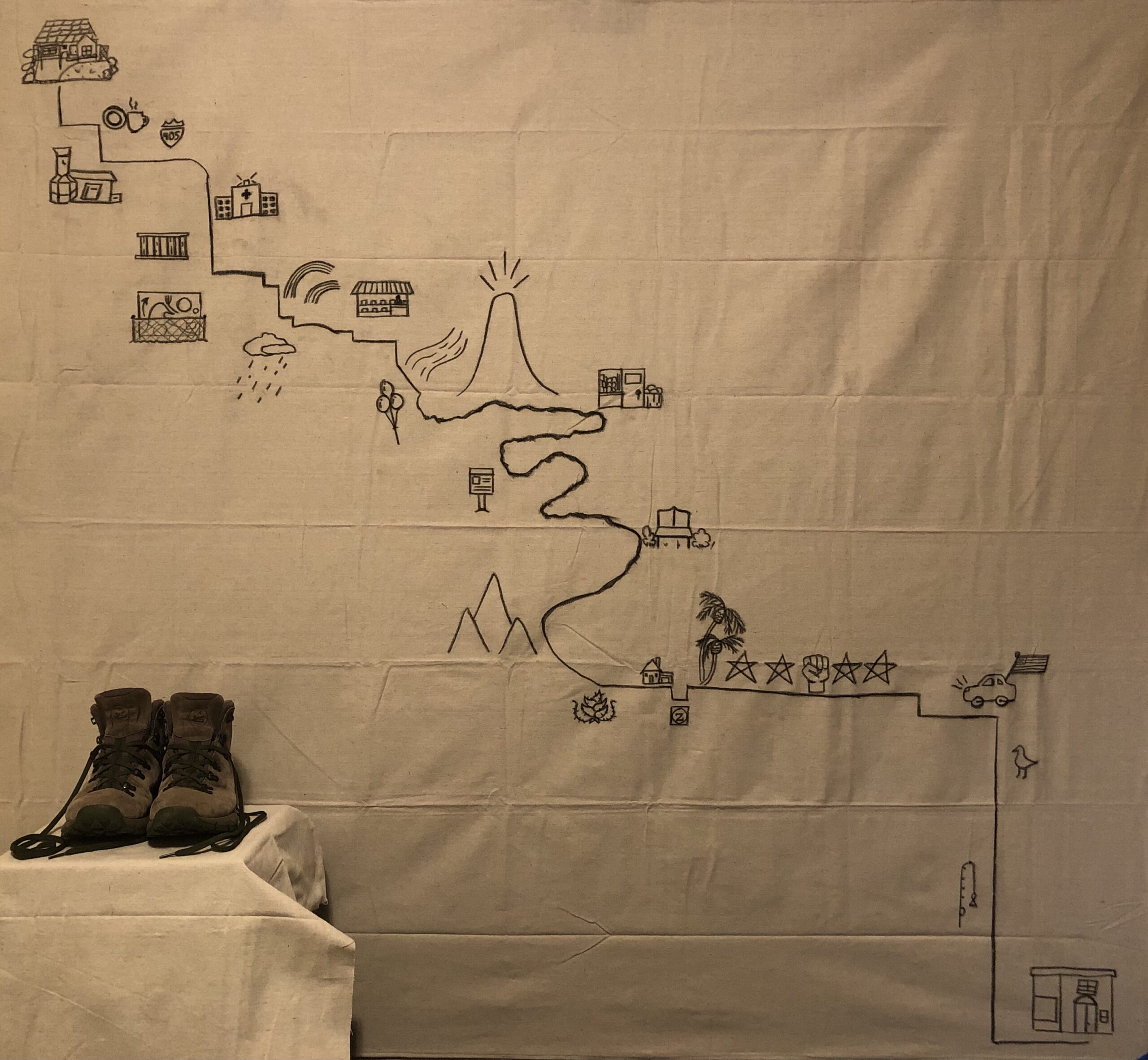 A large map hung on a wall with imagery and accompanied by a pair of hiking boots.