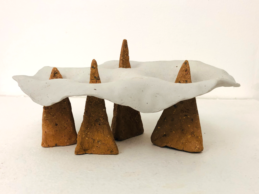Four triangular ceramic shapes holding a white cloud above them.